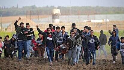 פלסטינים מפגינים ליד גדר הגבול בין ישראל לעזה. | EPA