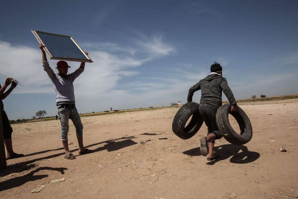פלסטינים עם צמיגים ומראות בגבול הרצועה. | AFP