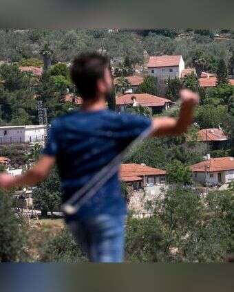 פלסטיני מיידה אבנים ביו"ש. | AFP פלסטיני מיידה אבנים ביו"ש. | AFP