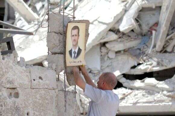 תמונה של אסד נתלית בהריסות בית בשכונה בדרום דמשק. | EPA