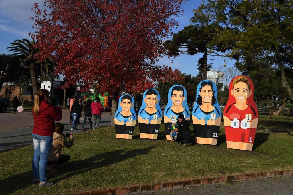 תיירים מצטלמים ליד בובות מטריושקה של כוכבי נבחרת אורוגוואי. | AFP