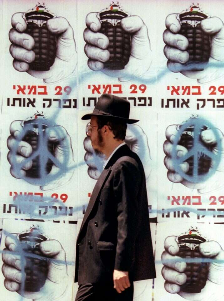 כרזות שמשוות את ערפאת לרימון יד תלויות על קיר ירושלמי לקראת בחירות 1999. | רויטרס