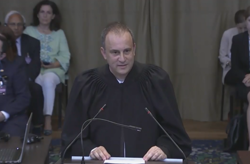 שיינדורף מעיד בבית הדין הבינלאומי בהאג. | מסך