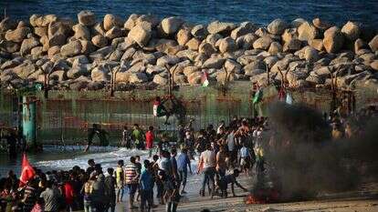 פורעים פלסטינים מטפסים על גדר הגבול. | AFP