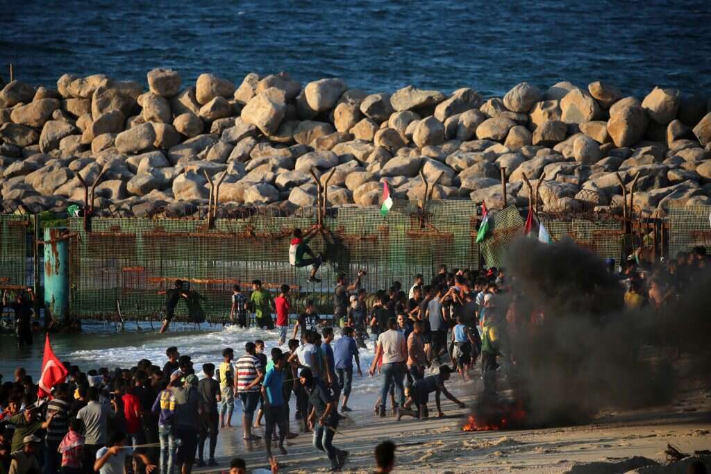 פורעים פלסטינים מטפסים על גדר הגבול. | AFP פורעים פלסטינים מטפסים על גדר הגבול. | AFP