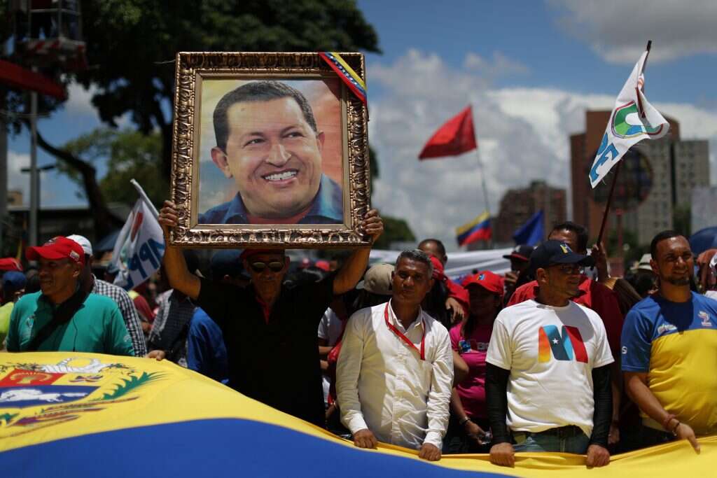 תומכי הממשל נושאים את תמונתו של הנשיא הוגו צ'אבז במהלך צעדה. | EPA