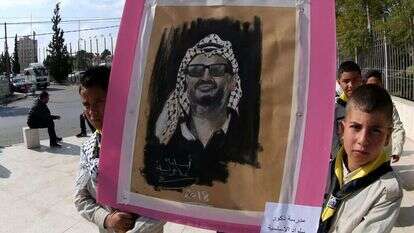 ילדים פלסטינים מניפים שלט לזכרו של יאסר ערפאת. | EPA