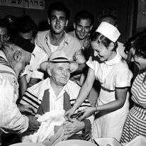 המילה שימשה כסימן זהותי המאפיין את אחרותו של העם היהודי. דוד בן גוריון משמש סנדק בברית המילה לילד הראשון שנולד באילת, 1952. | פריץ כהן, לע"מ