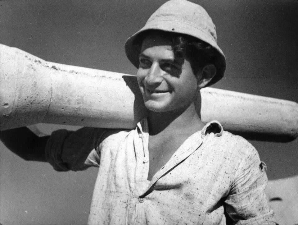 משה פלד בצעירותו (19) מניח צינור מים. בית אשל, 1944. | מתוך הספר. באדיבות ארכיון משפחת פלד