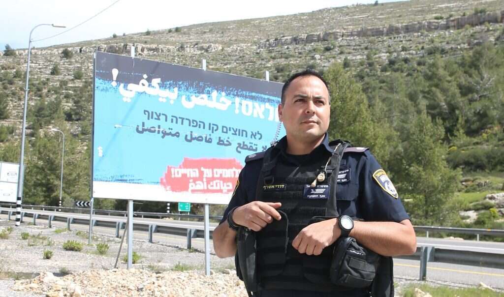 "הרבה פעמים ניגש אליי נהג פלסטיני ואומר 'אני חייב לשלם שבעה דו"חות, כי אני צריך היתר כניסה לישראל". רפ"ק אסרף ושלט פרסום לקידום נהיגה בטוחה. | מרים צחי