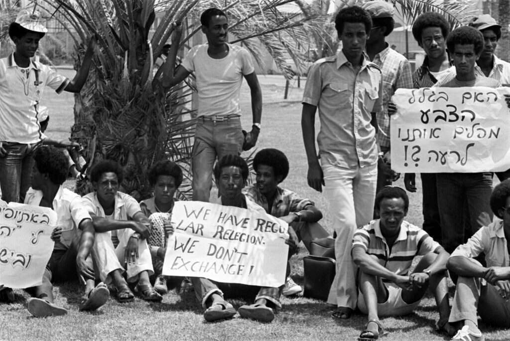דווקא הנרטיב הרבני מקל על ההכרה בבני הקהילה האתיופית כחלק מעם ישראל. הפגנה בשדה התעופה בן גוריון כחלק מהבקשה מהרבנות הראשית להתייחס אל עולי אתיופיה כאל יהודים, 1985. | AFP דווקא הנרטיב הרבני מקל על ההכרה בבני הקהילה האתיופית כחלק מעם ישראל. הפגנה בשדה התעופה בן גוריון כחלק מהבקשה מהרבנות הראשית להתייחס אל עולי אתיופיה כאל יהודים, 1985. | AFP
