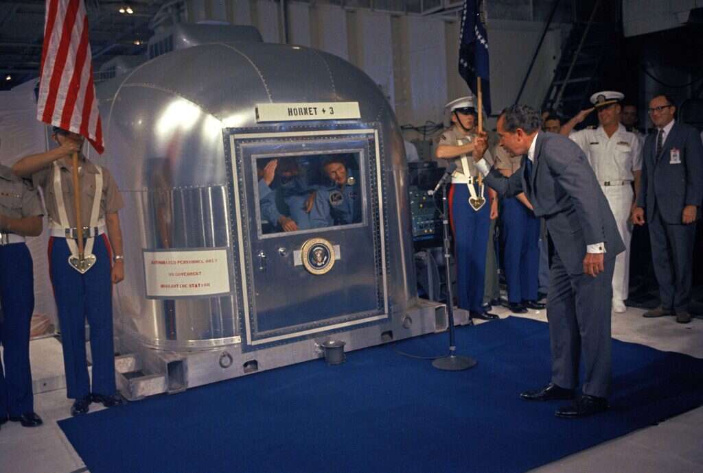 הנשיא ניקסון צופה בשלושה היושבים בתא המבודד. | AP