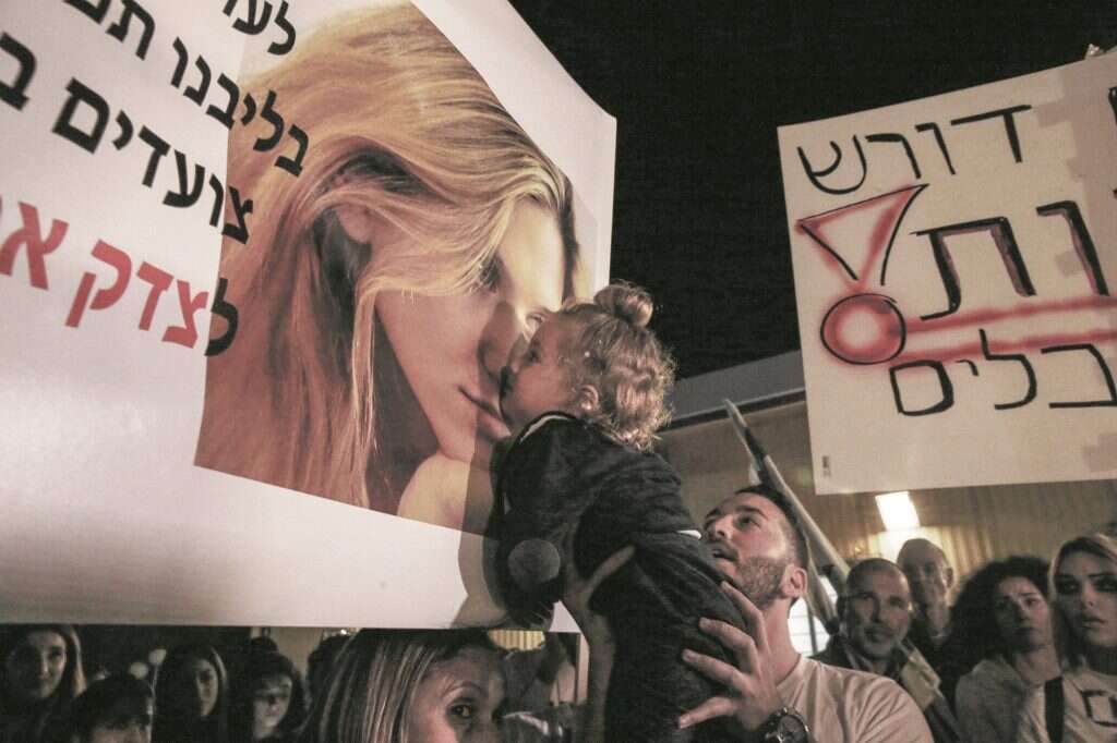 התינוק של קים לבנגרונד ז"ל מזהה את אמו בתמונה על כרזה בהפגנה. | מרים צחי