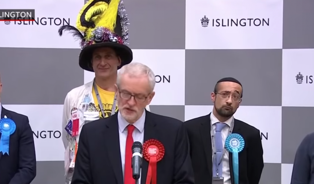 דוד יוסף (מימין) מאחורי קורבין, בסיום יום הבחירות בבריטניה. | מסך BBC NEWS דוד יוסף (מימין) מאחורי קורבין, בסיום יום הבחירות בבריטניה. | מסך BBC NEWS