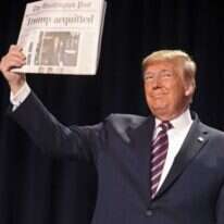 טראמפ מציג עיתון שכותרתו מכריזה על הזיכוי בסנאט. | AFP