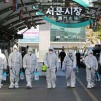 עובדי שוק בדרום קוריאה, מכוסים בחליפות מגן, מחטאים את המקום | AFP