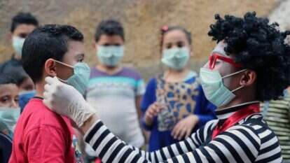 הליצן המצרי, אחמד נאסר מחלק מסיכות לילדים בקהיר. | EPA