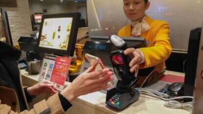 לקוח בבית עסק בסין משלם באמצעות הסמארטפון. | שאטרסטוק