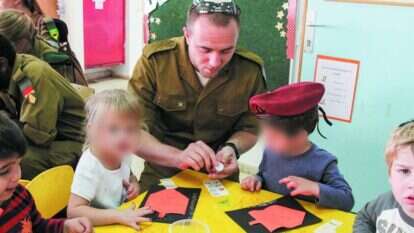 "ככל שהממסד הדתי ימשיך לראות בהם לא-יהודים, ייתכן שגם הם יפסיקו להיאבק על הגדרתם כיהודים". חייל בתהליך גיור מבקר בגן ילדים באפרת כדי ללמוד על חנוכה, 2013. | גרשון אלינסון, פלאש 90