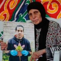 אמו של אלחלאק עם תמונתו. | AFP