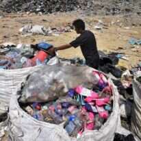 אספן אשפה אוסף פלסטיק למחזור באתר הטמנה בצפון תאילנד. | AFP