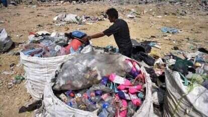 אספן אשפה אוסף פלסטיק למחזור באתר הטמנה בצפון תאילנד. | AFP