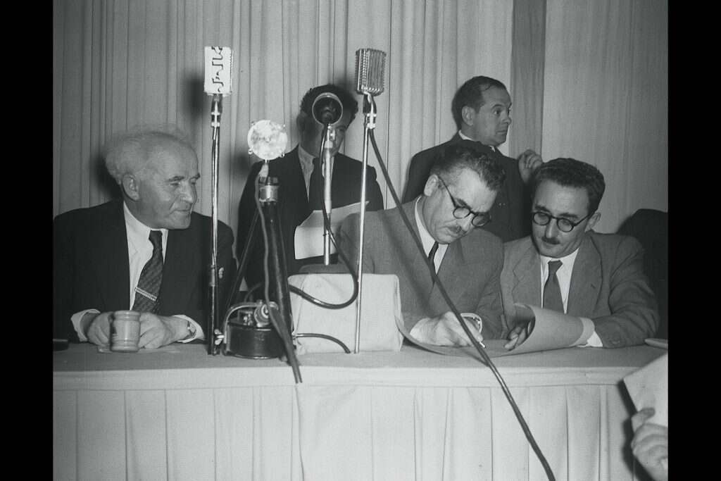 חלק מרגעים מכוננים בהיסטוריה. משה שפירא (באמצע) חותם על מגילת העצמאות. | פין הנס, לע"מ