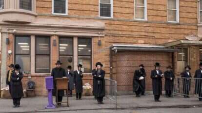 חסידים מתפללים בחוץ במסגרת השמירה על ריחוק חברתי בבורו פארק, 30 במארס. | אבי קיי