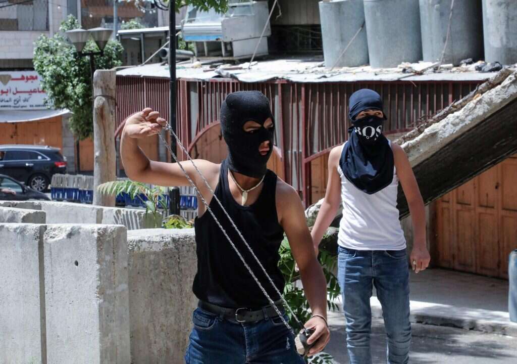 פלסטינים מיידים אבני כלפי כוח צה"ל בחברון בחודש שעבר. | AFP