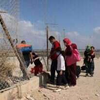 פלסטינים חוצים את הפירצה בגדר בדרך לים. | EPA
