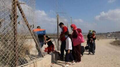 פלסטינים חוצים את הפירצה בגדר בדרך לים. | EPA
