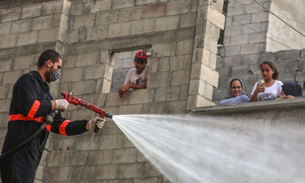 לא מבחינים בין דם לדם, אבל יש עדיפות למקומיים. עובד תברואה "מחטא את הרחוב מקורונה" בעזה. | EPA
