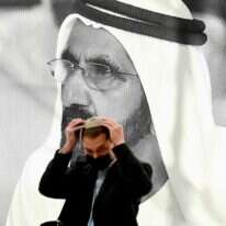 חבר במשלחת היי-טק ישראלית מסדר את הכיפה ליד פוסטר של מושל דובאי השייח מוחמד בין-ראשיד אל-מקטום. | AFP