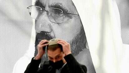 חבר במשלחת היי-טק ישראלית מסדר את הכיפה ליד פוסטר של מושל דובאי השייח מוחמד בין-ראשיד אל-מקטום. | AFP