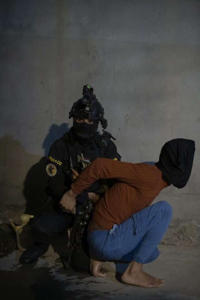 איש היחידה העירקאית ללוחמה בטרור אוחז באחיו של עיסאווי במהלך המעצר. | צ'רלס תיאפן, הוושינגטון פוסט