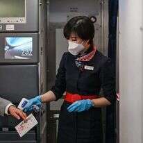 דיילת בודקת חום לנוסע בשדה התעופה בוואהן, סין. פברואר 2021. | AFP