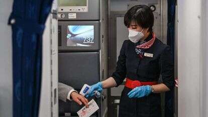 דיילת בודקת חום לנוסע בשדה התעופה בוואהן, סין. פברואר 2021. | AFP