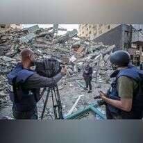 צוות טלוויזיה פלסטיני עובד לצד הריסות של בניין אלג'לאא, בניין התקשורת בעזה. | EPA