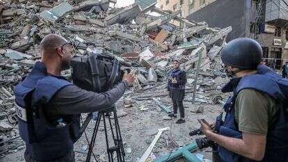 צוות טלוויזיה פלסטיני עובד לצד הריסות של בניין אלג'לאא, בניין התקשורת בעזה. | EPA