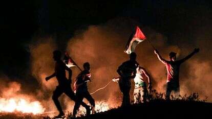 פלסטינים מתפרעים על גדר הגבול ברצועת עזה. | AFP