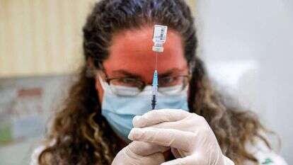 אחות בקופת חולים "כללית" מתכוננת לחסן נער נגד קורונה. | AFP