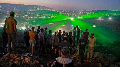 תושבי אביתר מביטים במפגינים פלסטינים, שמכוונים לעברם קרני לייזר. | AFP