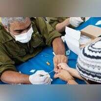 חייל מילואים מבצע בדיקה סרולוגית לילד בנתניה לקראת פתיחת שנת הלימודים. | AFP