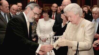 היהודים לא יוכלו להביא ברכה לעולם אם יתנתקו ממנו. הרב זקס מעניק חנוכייה למלכת בריטניה, 2006. | AP היהודים לא יוכלו להביא ברכה לעולם אם יתנתקו ממנו. הרב זקס מעניק חנוכייה למלכת בריטניה, 2006. | AP