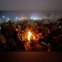 מהגרים על גבול בלארוס־פולין מציתים אש כדי להתחמם. | איי.אף.פי