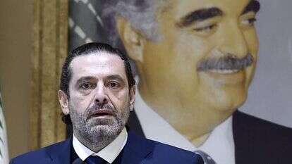 ראש ממשלת לבנון סעד אלחרירי מודיע על התפטרותו כשמאחוריו דיוקנו של אביו המנוח. | EPA