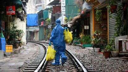 עובד בריאות הנושא ציוד רפואי הולך לאורך רחוב הרכבת של האנוי בהאנוי, וייטנאם. | EPA