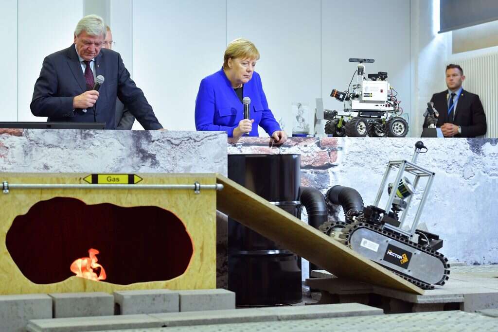 הרמוניה בין רובוטים, אלגוריתמים ובני אדם. קנצלרית גרמניה לשעבר אנגלה מרקל צופה ברובוט חילוץ והצלה בתחרות בהסן, 2018. | גטי אימג'ס