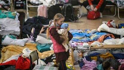ילדה מחזיקה את אחיה הפעוט במחנה פליטים בגבול אוקראינה-פולין. | AFP