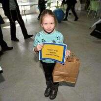 "פרצוף שמח שגם הם יהיו שמחים". ילדה מבית הילדים "עלומים" של קהילת ז'יטומיר באריזת משלוחי מנות. | חב"ד ז'יטומיר